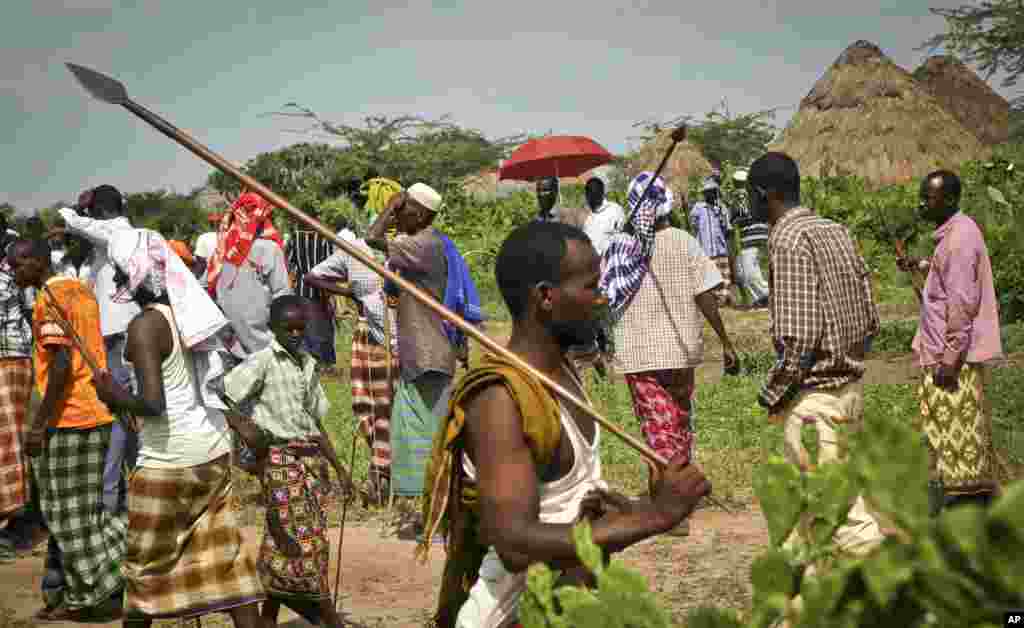A villager walks away armed with a spear after viewing the bodies of suspected attackers from the Pokomo tribe, not pictured, following tribal clashes in Kipao village in the Tana River Delta region.