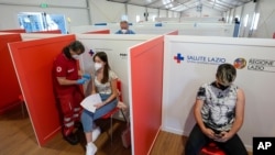 FILE - A young woman is administered her first dose of a COVID-19 vaccine, at a vaccination site set up in a shopping mall on the outskirts of Rome, Italy, June 1, 2021. 