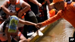 ARCHIVO - Un funcionario de protección civil ayuda a migrantes a bajar de un barco en Lajas Blancas, Panamá, el viernes 28 de junio de 2024, después de que cruzaron caminando el Tapón del Darién desde Colombia.