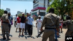 Polícias moçambicanos olham para os manifestantes que discutem com eles em Maputo, a 15 de janeiro de 2025, enquanto Daniel Chapo presta juramento para ser empossado como Presidente de Moçambique durante a sua tomada de posse na Praça da Independência.