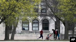 FILE - Pedestrians pass near the University of Chicago Monday, April 27, 2020, in Chicago.