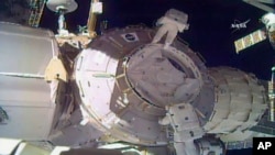 In this image made from video provided by NASA, U.S. astronauts Peggy Whitson, above, and Shane Kimbrough work on the outside of the International Space Station, March 30, 2017.