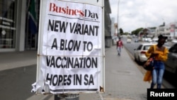 FILE - A woman walks past newspaper billboards telling of another COVID-19 outbreak in Johannesburg, South Africa, Feb. 8, 2021.