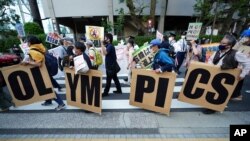 FILE - People opposing the Tokyo 2020 Olympics set to open in July amid the COVID pandemic, march near Tokyo's National Stadium, in Tokyo, Japan, May 9, 2021.