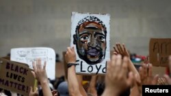 People hold up a likeness of George Floyd at a public memorial after his death in Minneapolis police custody, in the Brooklyn borough of New York City, New York, June 4, 2020.