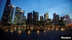 FILE - People walk past the skyline of Marina Bay central business district in Singapore, Apr. 26, 2013. 