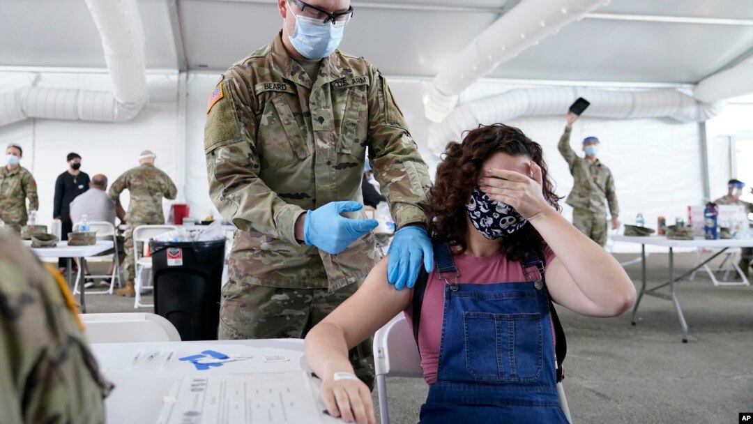 Leanne Montenegro, 21, covers her eyes as she doesn't like the sight of needles, while she receives the Pfizer COVID-19 vaccine at a FEMA vaccination center at Miami Dade College, Monday, April 5, 2021, in Miami.