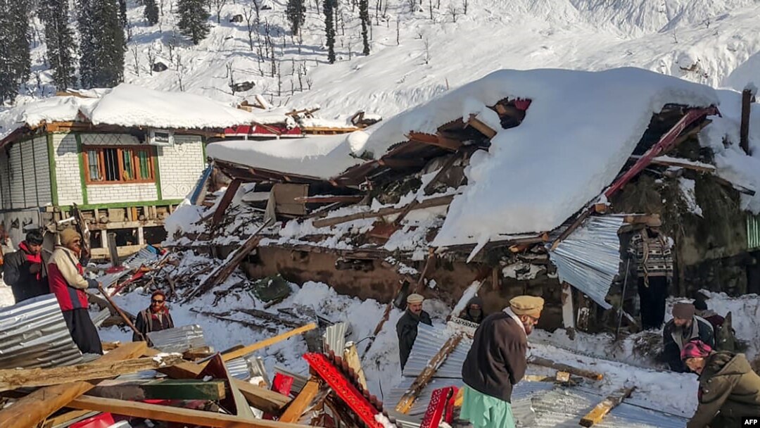 Penduduk setempat membuang puing-puing rumah yang runtuh akibat hujan salju lebat yang memicu longsoran salju di Lembah Neelum, di Kashmir, 14 Januari 2020 (Foto: AFP)