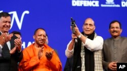 FILE - Indian Defense Minister Rajnath Singh holds a model of a light machine gun with Chief Minister of Uttar Pradesh state Yogi Adityanath, 2nd left, during DefExpo20 in Lucknow, Feb. 7, 2020.