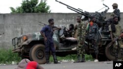 Sojoji masu goyon bayan Alassane Ouattara a tsaye kusa da wani mutumin da ya ji rauni a Abidjan, asabar 2 Afrilu, 2011.