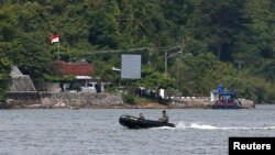 FILE - Indonesian military patrol in a small inflatable boat near a ferry boat dock on the prison island of Nusakambangan, in the background, in Central Java. March 3, 2015. Aman Abdurrahman is being held at Nusakambangan.