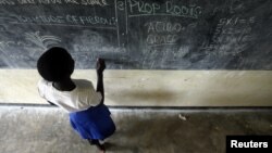 Grace Debroha, a 13-year-old orphan, writes the names of body parts on a chalkboard at St. Jude's Orphanage, outside Gulu, Uganda, June 2007 file photo.