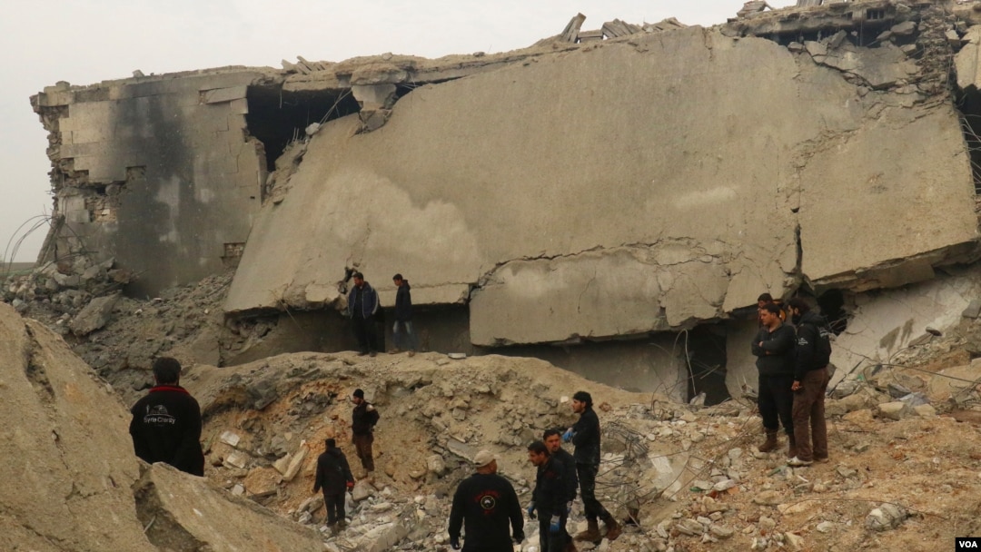 Civil defense members and other people inspect a damaged mosque after an airstrike on the village of al-Jinah, Aleppo province, in northwest Syria, March 17, 2017.