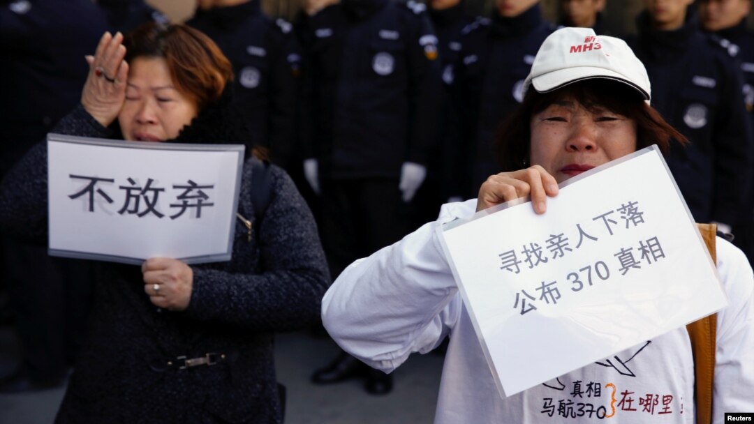 Para anggota keluarga penumpang pesawat MH370 yang hilang 8 Maret tahun 2014, membawa tulisan dalam unjuk rasa di Beijing