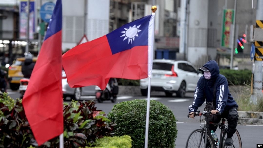 Seorang pengendara sepeda di samping dua bendera nasional Taiwan di Taipei. (Foto: AFP)