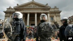 Polisi Anti Huru-hara mengenakan pakaian pelindung dalam peringatan untuk para korban serangan di Brussels dekat Place de la Bourse, Brussels (27/3).