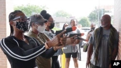 In this Aug. 21, 2021, image taken from video, firearms instructor Wayne Thomas instructs women the proper stance in firearms shooting at the Recoil Firearms store in Taylor, Mich.