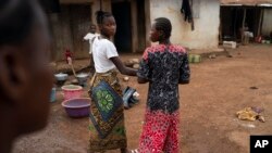 Marie walks with a friend on a street in Komao village, on the outskirts of Koidu, district of Kono, Sierra Leone, Sunday, Nov. 22, 2020. (AP Photo/Leo Correa)