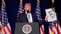 President Donald Trump holds up a sign given to him by a supporter during a rally for evangelical supporters at the King Jesus International Ministry, Jan. 3, 2020, in Miami.