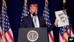 President Donald Trump holds up a sign given to him by a supporter during a rally for evangelical supporters at the King Jesus International Ministry, Jan. 3, 2020, in Miami.