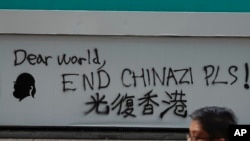 A man walks past a wall with the words "Liberate Hong Kong- Dear World End Chinazi Please" in Hong Kong, Oct. 7, 2019.