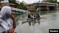 FILE - Villagers ride on a boat to cross a river after bridge was damaged in Loon, Bohol, Oct. 16, 2013, a day after an earthquake hit central Philippines. 