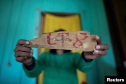 FILE - An indigenous woman of the Uru-eu-wau-wau tribe shows a piece of wood with a lot number removed from an area deforested by invaders in the village of Alto Jaru, at the tribe's reservation, near Campo Novo de Rondonia, Brazil, Feb. 1, 2019.