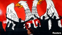 A woman walks past a graffiti depicting part of the Serbian coat of arms in the northern Serb dominated, part of the ethnically divided town of Mitrovica, Kosovo, April 3, 2013.