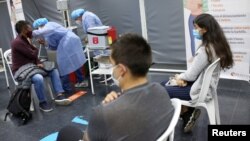 A man receives the first dose of the AstraZeneca COVID-19 vaccine as the Colombian government begins the vaccination campaign for people between 20 and 24 years old, in the newspaper library of the National University in Bogota, Aug. 15, 2021.