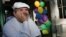 FILE - Chef Paul Prudhomme sits in front of his restaurant 'K-Paul's Louisiana Kitchen' in the French Quarter, in New Orleans, Louisiana, Oct. 18, 2005. 