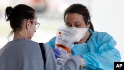 Raeanne Castillo, at right, with Roper St. Francis Healthcare gives specimen collection kits to a LabCorp employee at the hospital's North Charleston office, South Carolina, March 16, 2020.