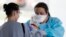 Raeanne Castillo, at right, with Roper St. Francis Healthcare gives specimen collection kits to a LabCorp employee at the hospital's North Charleston office, South Carolina, March 16, 2020.