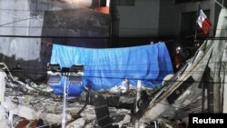 Members of rescue team place a blue tarp and a Mexican flag as they remove the last body trapped under rubble of a collapsed building at Alvaro Obregon Avenue in the Condesa neighborhood, after an earthquake in Mexico City, Mexico, Oct. 4, 2017. 