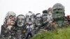 Seorang pengunjung berjalan melewati patung yang dibuat dari limbah elektronik yang menyerupai Gunung Rushmore dan para pemimpin G-7 di sebuah bukit di Hayle, Cornwall, Inggris, Rabu, 9 Juni 2021. (Foto: AP/Jon Super)