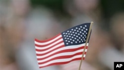 A new U.S. citizen waves a small flag during a naturalization ceremony at Walt Disney World in Lake Buena Vista, Fla., Wednesday, July 4, 2007. Over one thousand immigrants became citizens.(AP Photo/John Raoux)