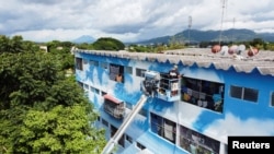 A drone view shows members of the Fullpaint 360 collective painting clouds on a building in Mejicanos, El Salvador, Aug. 13, 2024.