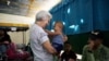 La hermana Rosita sostiene a Alexander Solis y saluda a los refugiados y migrantes venezolanos mientras esperan para recoger los kits de higiene y nutrición donados por el IMDH en la Casa de Acolhida São José, en Pacaraima, Brasil. [Foto: ACNUR]