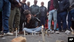 Iraqis gather around a crying man who lit candles by the spot where an Iraqi protester was killed Friday, at Khilani square, in Baghdad, Iraq, Dec. 7, 2019.