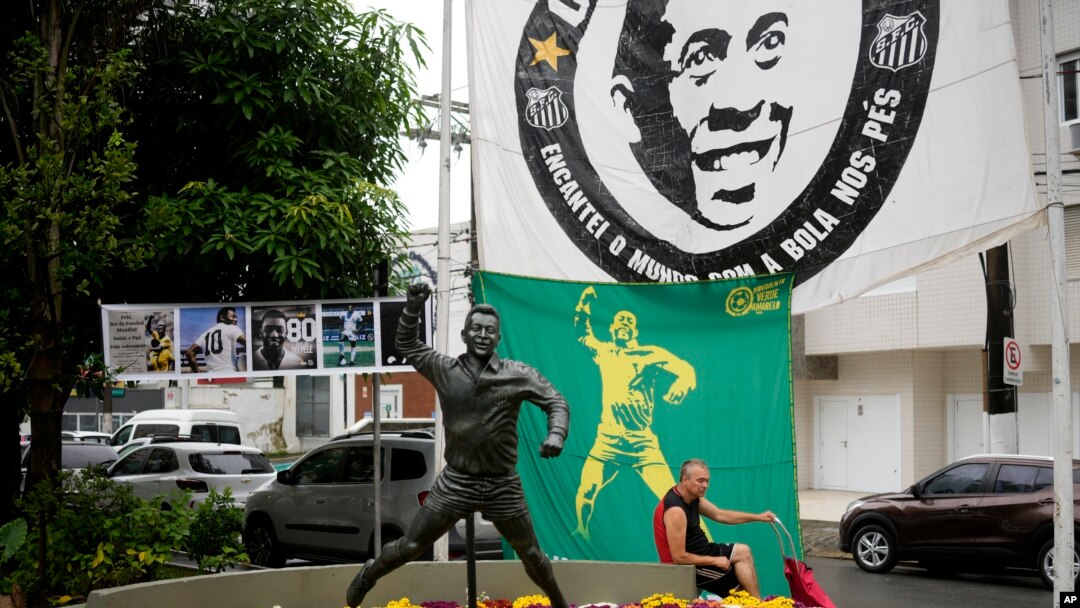 Seorang pria duduk di sebelah patung Pele, bintang sepak bola Brazil di Santos, Brazil, Jumat, 30 Desember 2022. Pele meninggal dunia di São Paulo pada usia 82 tahun, 29 Desember 2022. (AP/Matias Delacroix)