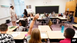 ARCHIVO - Un estudiante levanta la mano en un salón de clases de la escuela primaria Tussahaw el 4 de agosto de 2021 en McDonough, Georgia.