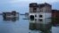 FILE - Indians watch from the upper floor of their house flooding in the river Ganges in Allahabad, India, Aug. 23, 2016.