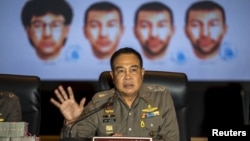 Thai national police chief Somyot Pumpanmuang gestures during a news conference about the Bangkok blast which killed 20 people, including foreigners, as a screen shows the different looks of a suspect, who has been referred to both as Bilal Mohammed and Adem Karadag, the name on a Turkish passport he holds, at the Royal Thai Police headquarters in central Bangkok, Thailand, Sept. 28, 2015.