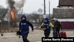 Журналісти тікають у прикриття після потужних обстрілів єдиного шляху евакуації місцевих жителів в Ірпіні, поблизу Києва, Україна, 6 березня 2022 року. REUTERS/Carlos Barria