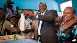 Kenyan Presidential candidate Uhuru Kenyatta casts his vote, accompanied by his wife Margaret Wanjiru Gakuo (R), at the Mutomo primary school near Gatundu, north of Nairobi, in Kenya, March 4, 2013.