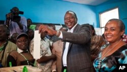 Kenyan Presidential candidate Uhuru Kenyatta casts his vote, accompanied by his wife Margaret Wanjiru Gakuo, right, at the Mutomo primary school near Gatundu, north of Nairobi, in Kenya, March 4, 2013.