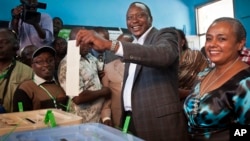 Kenyan presidential candidate Uhuru Kenyatta casts his vote, accompanied by his wife Margaret Wanjiru Gakuo, right, at the Mutomo primary school near Gatundu, north of Nairobi, March 4, 2013.