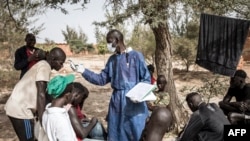 Les enfants de rue se font prendre leur température en zone de quarantaine, dans un refuge pour enfants de rue nouvellement arrivés à l'extérieur de Dakar, le 10 avril 2020.