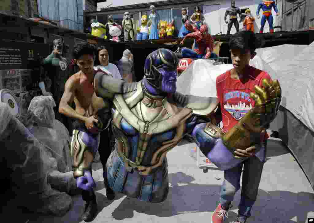 Workers carry a life-sized figure of Thanos, a character in the popular movie &#39;Avengers,&#39; as they prepare to display it outside their shop in Manila, Philippines.