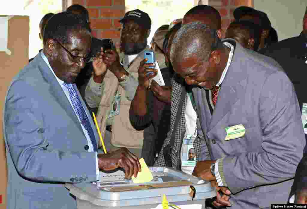 Zimbabwe&#39;s President Robert Mugabe (L) cast his vote as an election officer looks on in Highfields outside Harare July 31, 2013.