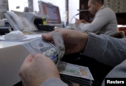 FILE - A money changer counts out U.S. dollars for a customer in Tehran's business district, Iran, Jan. 20, 2016.